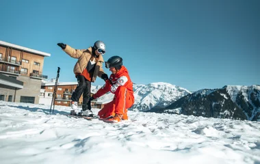 moniteur de ski chaussant un enfant