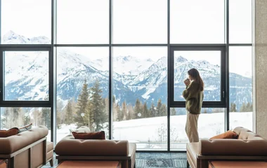 Femme buvant un chocolat chaud en regardant les pistes depuis notre Resort de la Rosière