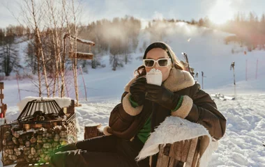 Femme en terrasse buvant un chocolat chaud à la montagne