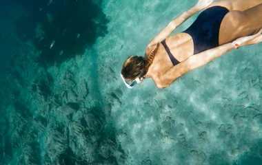 A man and a woman walking on a beach with palm trees