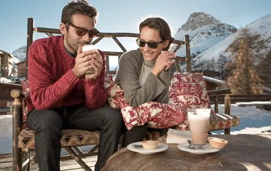 couple qui prend un chocolat chaud au soleil à la montagne