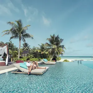 couple lying by the pool overlooking the ocean