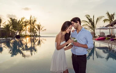 Una coppia in abiti freschi estivi davanti a un panorama delle Maldive al tramonto