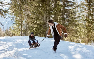 father and sone pulling sled in the Alps