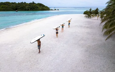 Surfers walking on the beach in the Maldives