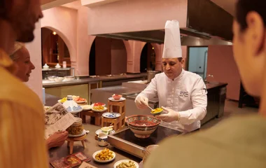 Un chef preparando comida tradicional delante de los invitados.