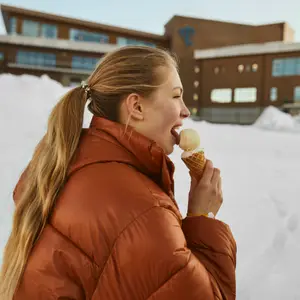 mulher de casaco na neve tomando sorvete de casquinha