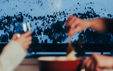 Pareja cenando fondue en la nieve.