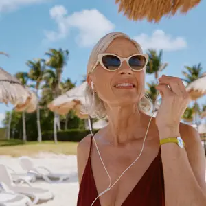 senhora em praia de óculos de sol e fones de ouvido
