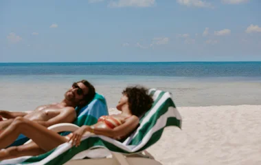 Casal em espriguiçadeira na beira da praia.