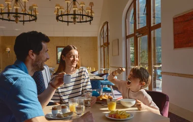 Uma família sentada à mesa fazendo uma refeição.