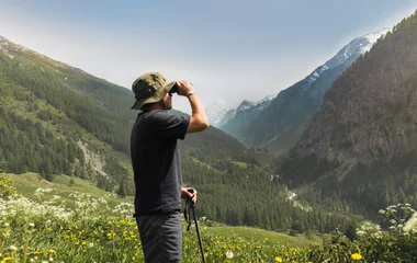 Pessoa com um binóculos admirando a vista enquanto faz uma trilha.