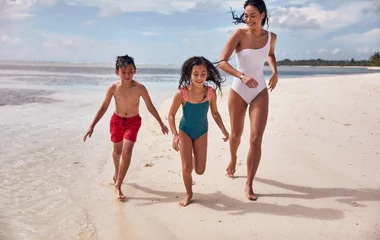 Mutter und Kinder rennen am Strand