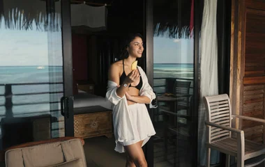 Frau schaut aus dem Zimmer zum Meer raus