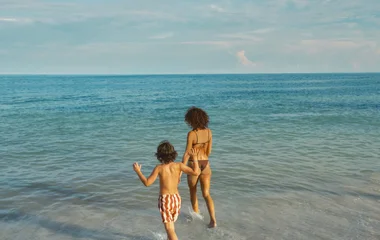 Mãe e filho entrando nas águas quentes do Caribe em praia em Punta Cana