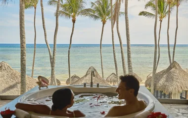 Casal dentro de uma banheira em um cenário paradisíaco.