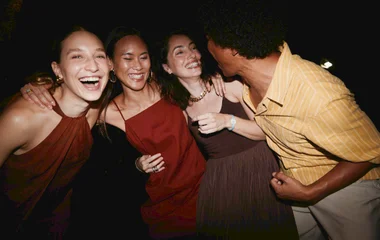 Um grupo de amigos abraçados posando para a foto enquanto curtem uma festa