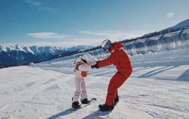 Moniteur de ski avec un enfant en snowboard