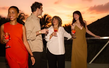 Hóspedes aproveitando férias ao pôr do sol com drinks na mão