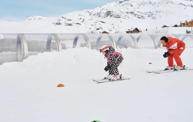 Niña en clase de esquí con instructor.