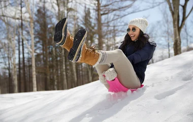 Pessoa se divertindo enquanto desliza pela neve em uma prancha.