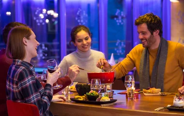 Grupo de amigos comendo um clássico fondue francês no Club Med Val Thorens.
