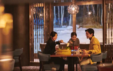 Family having dinner with snow in the background from the window.